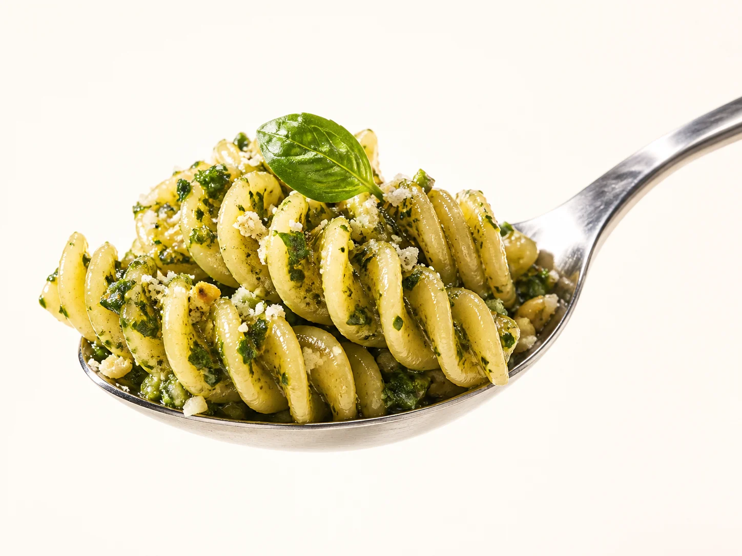 Pesto-coated Fusilli lifted on a silver serving spoon