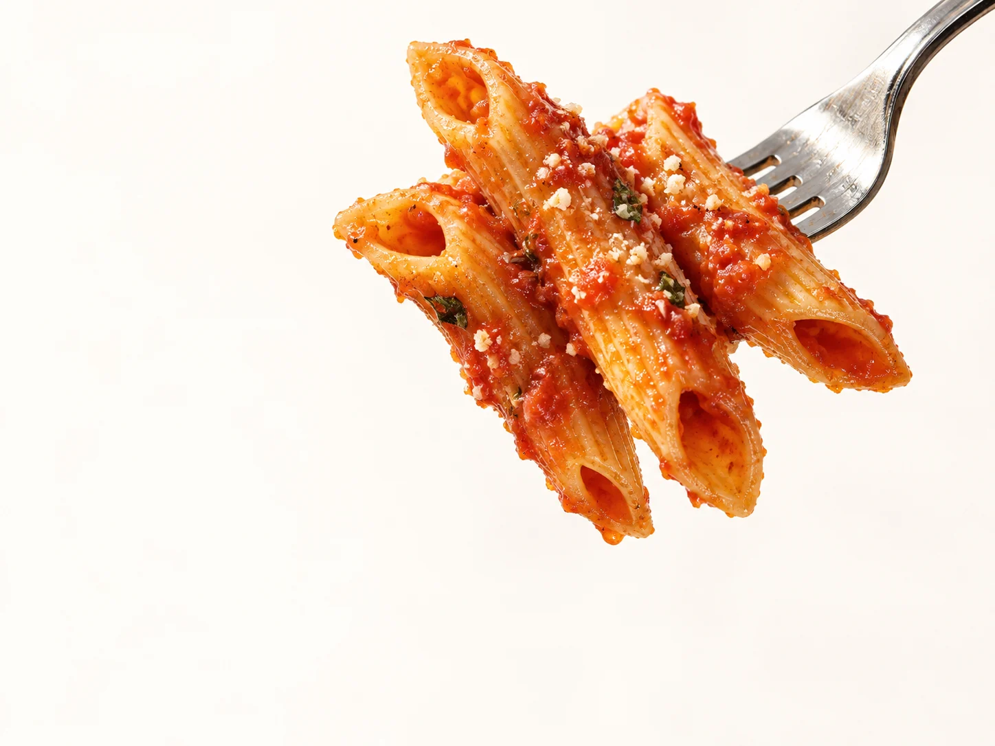 A fork lifting ridged Penne coated in tomato sauce